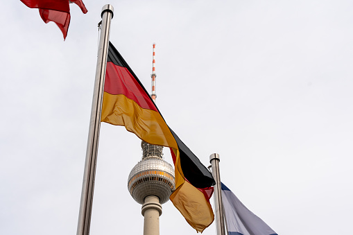 The German flag against the background of the Berlin television tower. Germany flag close up.