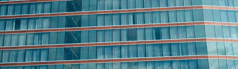 Exterior panorama view facade modern high rise hotel glass wall blackout curtains against sunny cloud blue sky in Texas, lookup view office building, skyscraper, futuristic looking architecture. USA