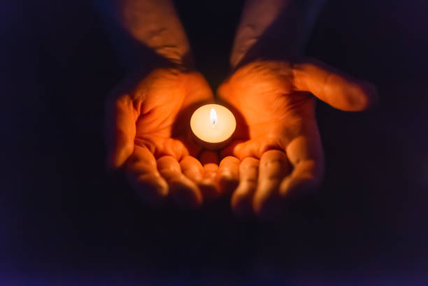istock Burning candle in a mans hand religion concept.Candle in hands on a dark background. 2149114056