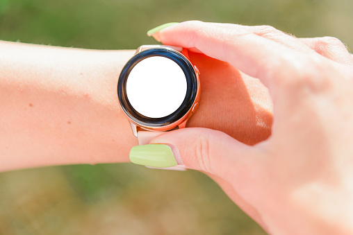Woman checking smart watch with blank screen mockup in wilderness, closeup.empty white screen mockup.