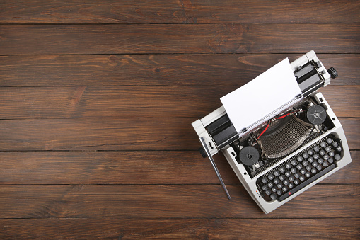 vintage typewriter on the table with blank paper on wooden desk - concept for writing, journalism, blogging