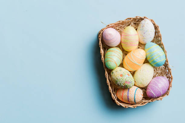 istock Colorful Easter eggs in wicker basket against colored background, closeup. top view with copy space 2149116629