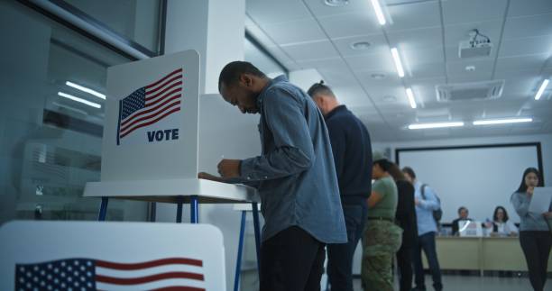 istock African American man votes in booth in modern polling station 2149116909