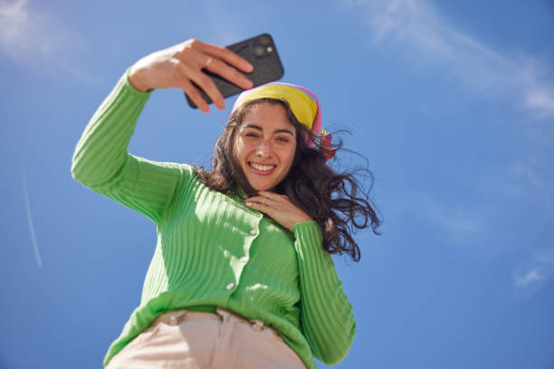istock Stylish Connectivity: Beautiful Youth with Smartphone Under Blue Sky 2149119337