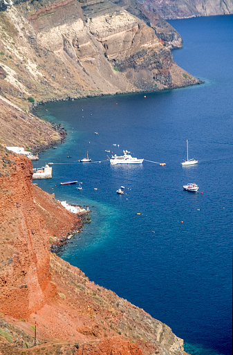 View of the seawater-filled volcanic crater on the Greek island of San Turin with anchored boats, excursion boats and yachts