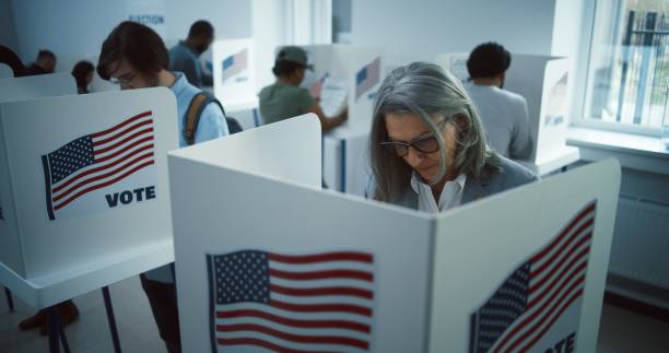 istock Elderly woman votes in booth in polling station office 2149123469
