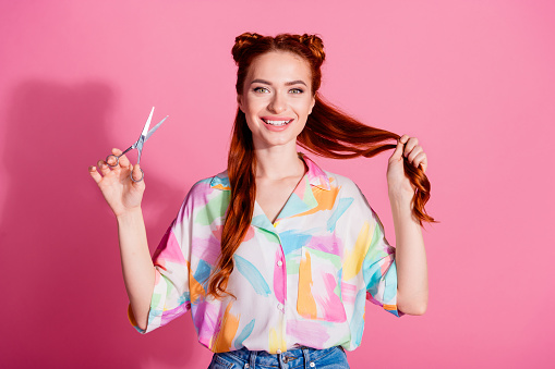 Photo of cheerful pretty girl dressed colorful blouse hand hold red tails scissors want to cut hairdo isolated on pink color background.
