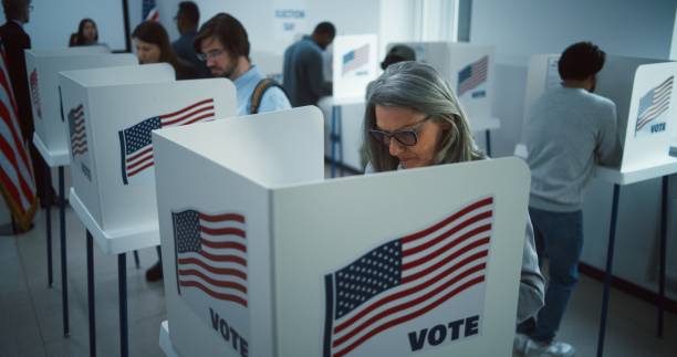 istock Elderly woman votes in booth in polling station office 2149124250