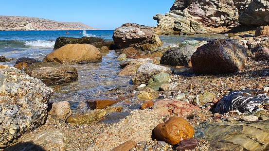 Colored stones on the shore of the Libyan Sea against the blue sky.