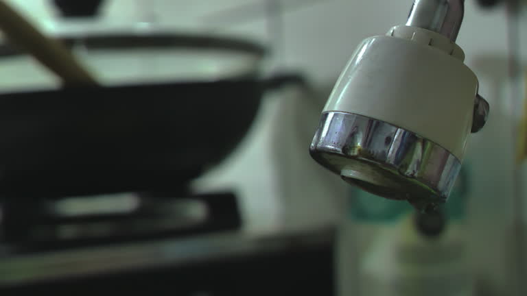 The sink faucet leaks and drips water in the dirty and dark kitchen, depicting a slovenly and neglected home