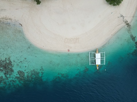 Drone image of a Coron island and a boat in the water and two people stretched out barely visible