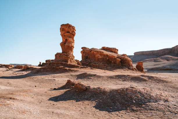 A striking rock sculpture stands prominently in Vallecito amidst the barren landscape of the Atacama Desert, Chile, under a clear blue sky.