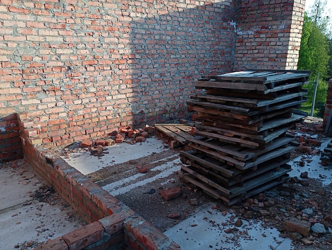 Old wooden pallets stacked on top of each other in an unfinished building site. thematic construction of houses and housing for people.