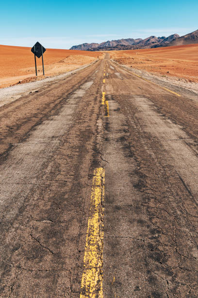 Vibrant image capturing an open road stretching through the Atacama Desert in Chile under a clear blue sky, evoking a sense of adventure and exploration.