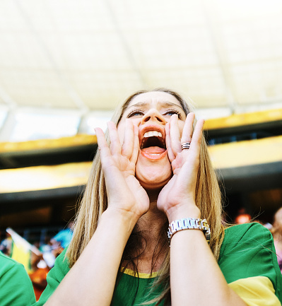 Enthusiastic young woman shouts for her team in a sports stadium.