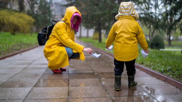 istock It's springtime. A small child in rubber boots jumps through puddles, plays and launches paper boats on the water. 2149128453
