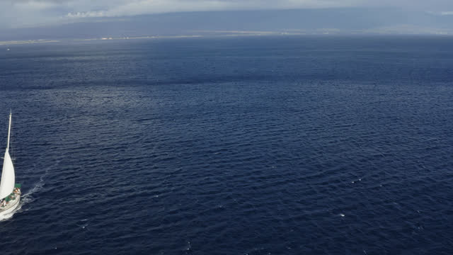 Drone dolly view of a white sailing boat sailing on the Auau Channel near Lahaina, Maui in Hawaii.