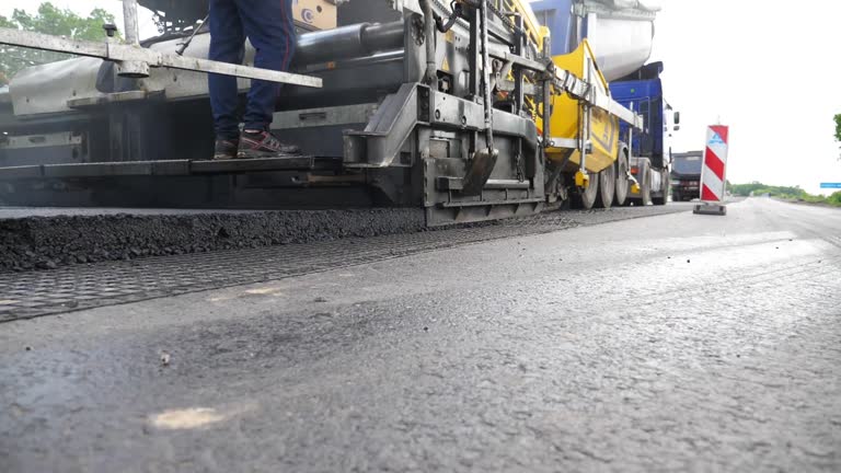 Slowly driving roller laying new asphalt layer. Special machinery making road in countryside area. Compactor constructing highway. Heavy machinery repairing road. Roadwork process. Roadway repair