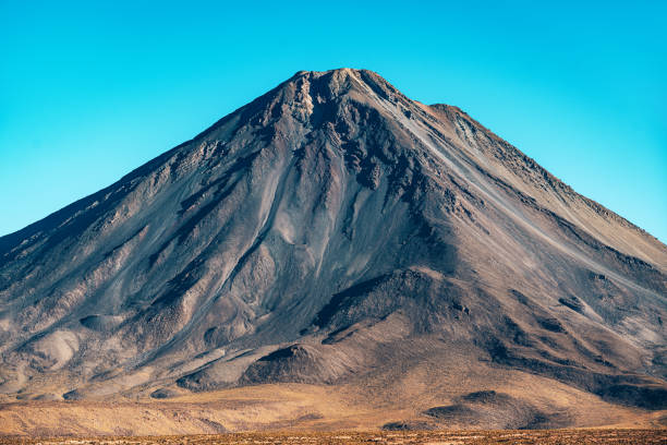 Stunning view of a majestic volcanic cone in the Atacama Desert, Chile, with a clear blue sky backdrop. Peaceful desert landscape showcasing nature's beauty.
