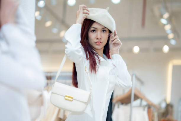 Portrait of a fashionable woman wearing a beret while perusing through clothes in a modern boutique setting.