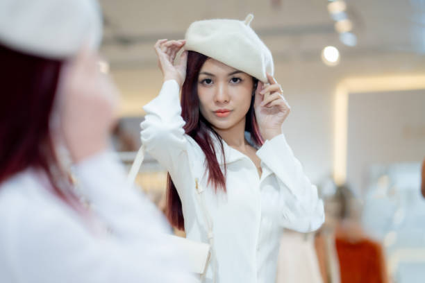 Portrait of a fashionable woman wearing a beret while perusing through clothes in a modern boutique setting.