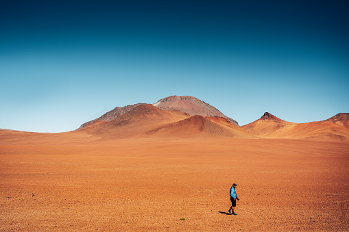 A lone traveler wanders across the endless expanse of the Atacama Desert in Chile, showcasing the beauty and isolation of this desolate landscape.