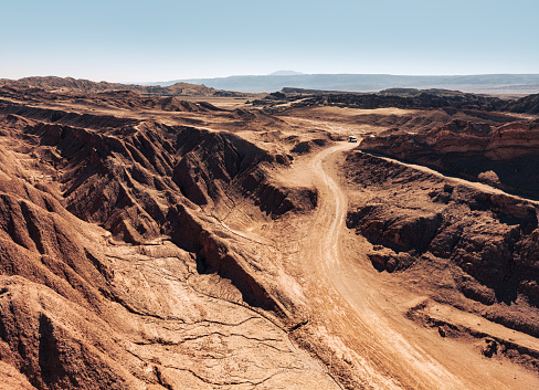 A captivating aerial view of a serpentine road snaking through the arid, rugged terrain of the Atacama Desert in Chile, showcasing a remote landscape.