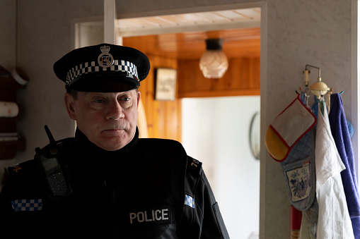 A policeman entering an elderly person's home.