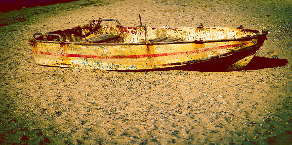 A beached boat lies alone on the beach, trying to survive with the wear and tear of time.
