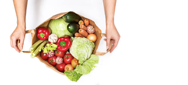 Female hands open a paper bag filled with various vegetables isolated on a white background. Delivery and purchase of healthy eco food Female hands open a paper bag filled with various vegetables isolated on a white background. Delivery and purchase of healthy eco food. Top view, copyspace of the right, horizontal banner deep pick stock pictures, royalty-free photos & images