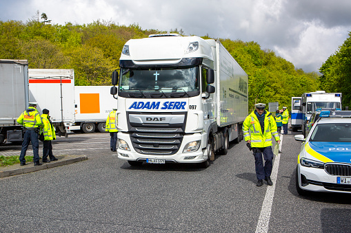Niedernhausen, Germany - April 17, 2024: Truck traffic control at German highway A3. The focus of the control is the monitoring of commercial freight transport as part of a safety campaign in collaboration with the German police and the Federal Office for Logistics and Mobility (BALM). BALM (formerly known as BAG) is the German Bundesamt fuer Logistik und Mobilitaet (Federal Logistics and Mobility Office). With over 500,000 truck and bus inspections every year, the road inspection service of the Federal Office for Logistics and Mobility makes an important contribution to increasing road safety and environmental protection.