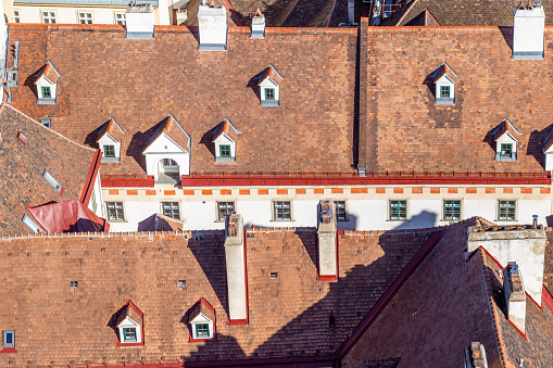Aerial view of narrow street in old Vienna among historical red tiled roof with irregularly placed dormers and chimneys