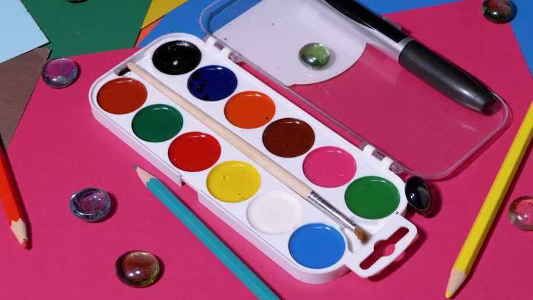 A Palette of Watercolors, Colored Pencils, Colored Cardboard Scattered on Table