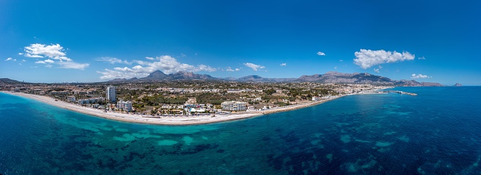 Wide angle aerial drone photo of the Spanish town of L'Albir in Spain Alicante showing the beach front on a sunny summers day with the Spanish mountains in the background