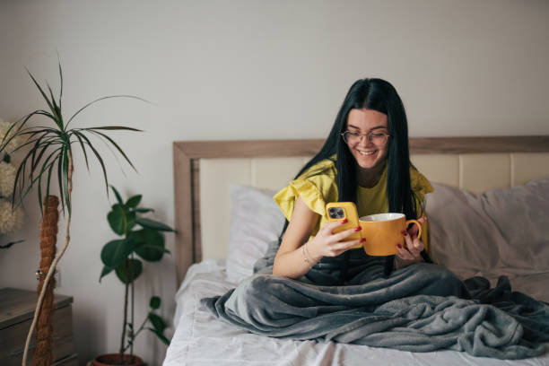 istock A young woman is having breakfast in bed and using her smartphone. 2149135498