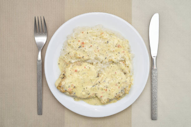 Grilled chicken breast fillets with cooking cream and herb spices with rice side dish on the white plate. Top view.