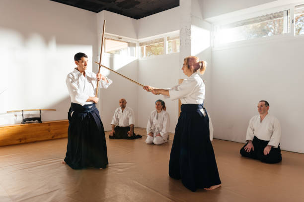 istock Aikido Female Instructor Demonstrates Jo Staff Techniques to Attentive Students in a Dojo 2149138459