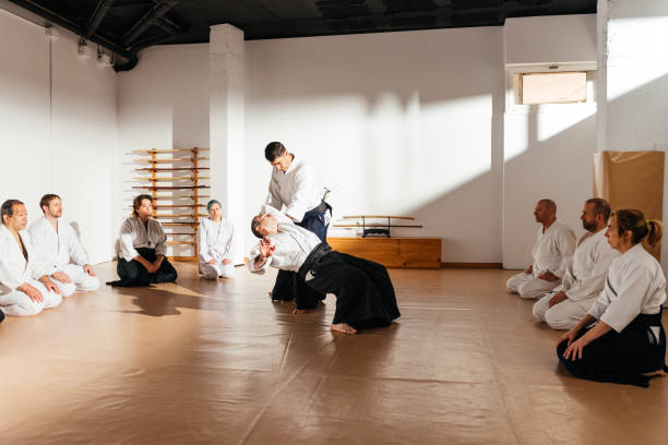 istock Martial Arts Sensei Demonstrates a Throwing Technique to Attentive Students in Sunlit Dojo 2149138625