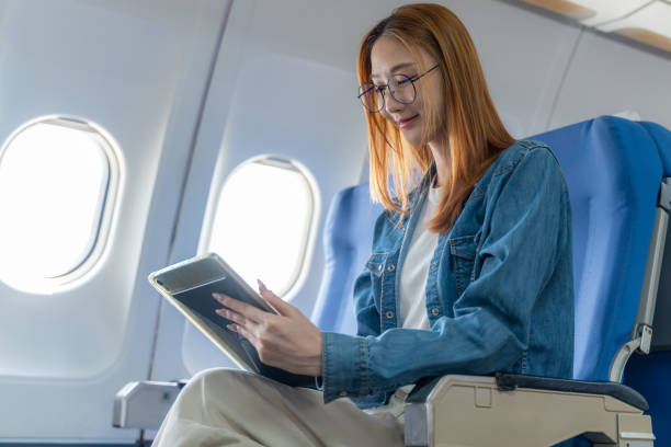 istock Happy young woman using her tablet while sitting alone on the plane by the window 2149138730