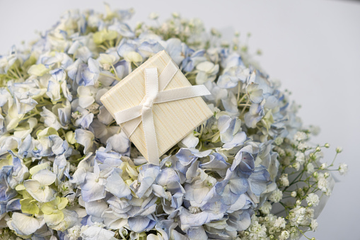 A gift box on a bouquet of hydrangea flowers on a white background.