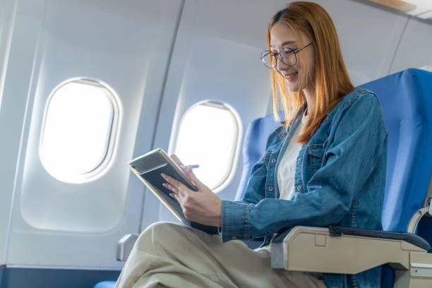 istock Happy young woman using her tablet while sitting alone on the plane by the window 2149139589