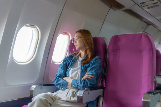 istock Tired young woman sitting by the window on the plane alone sleeping 2149141071