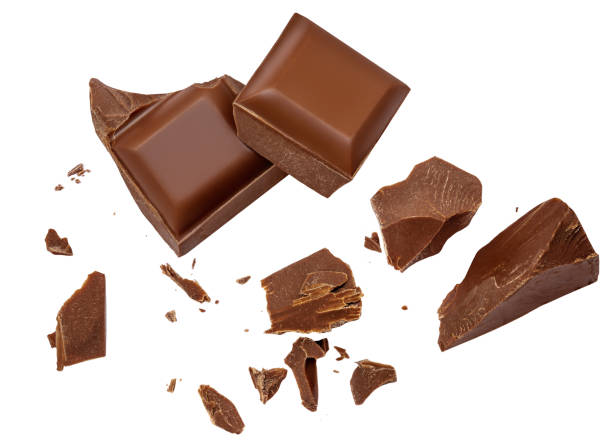  Levitating milk chocolate chunks isolated on white background. Crumbs, shavings and Flying Chocolate pieces Top view. Flat lay