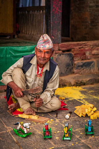 Nepali man making wooden rocking horses near the Bhaktapur Durbar Square. Bhaktapur is an ancient town in the Kathmandu Valley and is listed as a World Heritage Site by UNESCO for its rich culture, temples, and wood, metal and stone artwork.