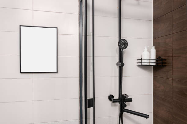 istock Modern bathroom with a black shower, shelf with shampoo bottles and a picture frame against white tiles. 2149141950