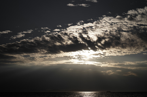 sun closed by clouds, bright sunlight reflected in the sea