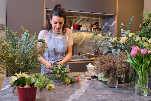 istock Female florist in apron cutting flowers 2149143239