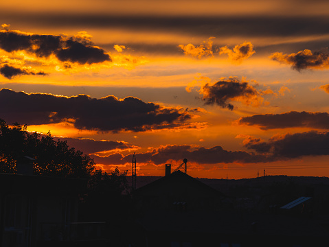 Fiery sunset silhouettes a tranquil town, with clouds ablaze in golden hues