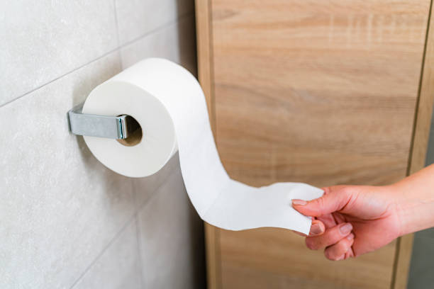 Close up of woman hand pulling paper roll from holder. High resolution 42Mp indoors digital capture taken with SONY A7rII and Zeiss Batis 40mm F2.0 CF lens