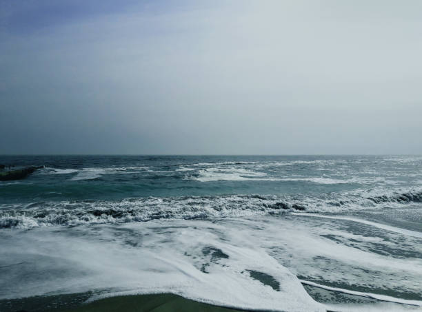 foam produced from waves on the beach. White foam from sea water on the beach. The waves turn the water into white foam
